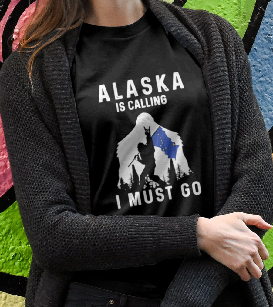 Alaska Is Calling I Must Go Bigfoot Holding Alaska Flag T-Shirt